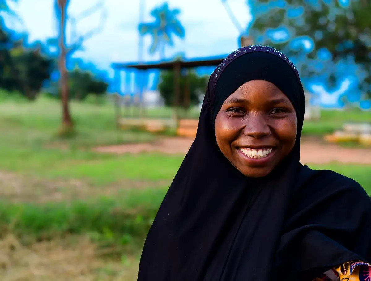 Mulher sorridente de lenço preto, ao ar livre