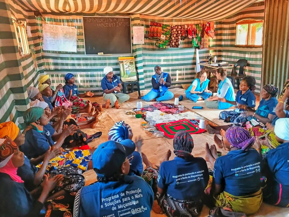 Mulheres sentadas em círculo dentro da tenda de um espaço seguro, com artesanato no chão