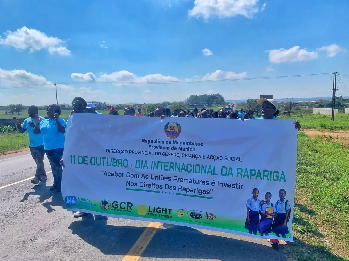 Marcha do Dia Internacional da Rapariga numa estrada, atrás de uma faixa contra as uniões prematuras