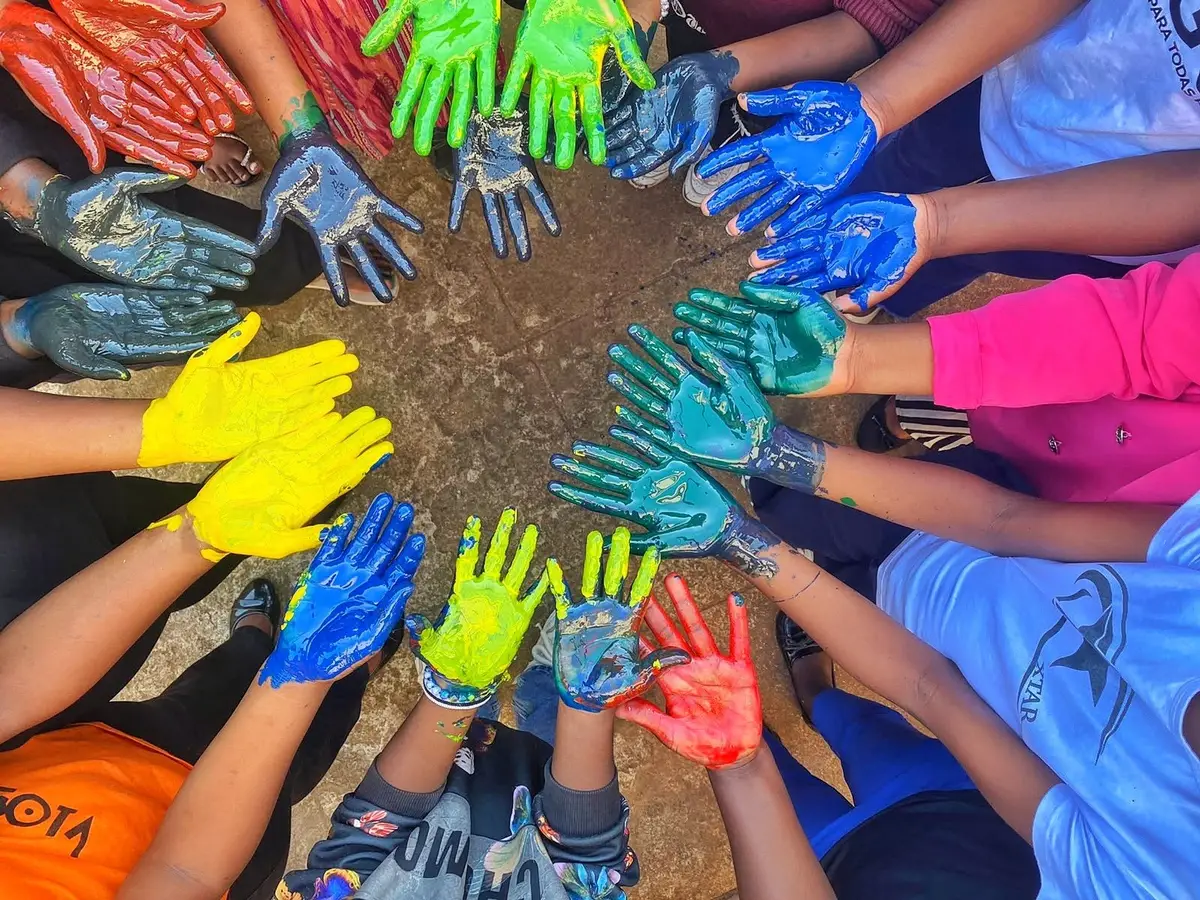Mãos pintadas de várias cores juntas em círculo, vistas de cima