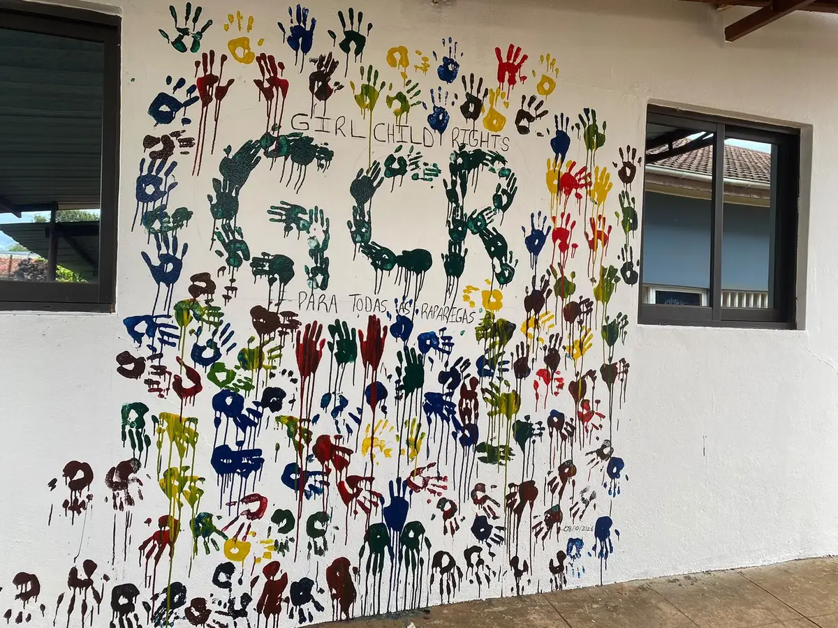 Parede coberta de mãos coloridas que formam «GCR para todas as raparigas»