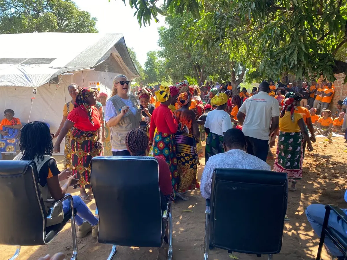 Convidados sentados diante da tenda do novo espaço seguro durante a inauguração em Cuamba, vistos de costas